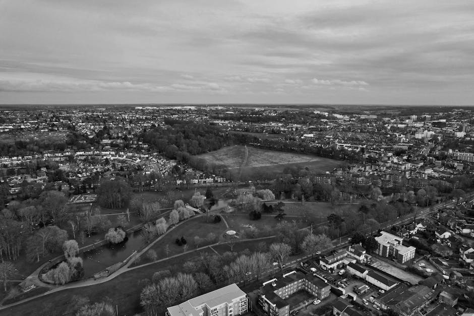 Aerial view of a residential area near Watford Junction railway station in Watford, UK, showing a busy urban landscape with rows of houses and small gardens on the right, and a large industrial buildi